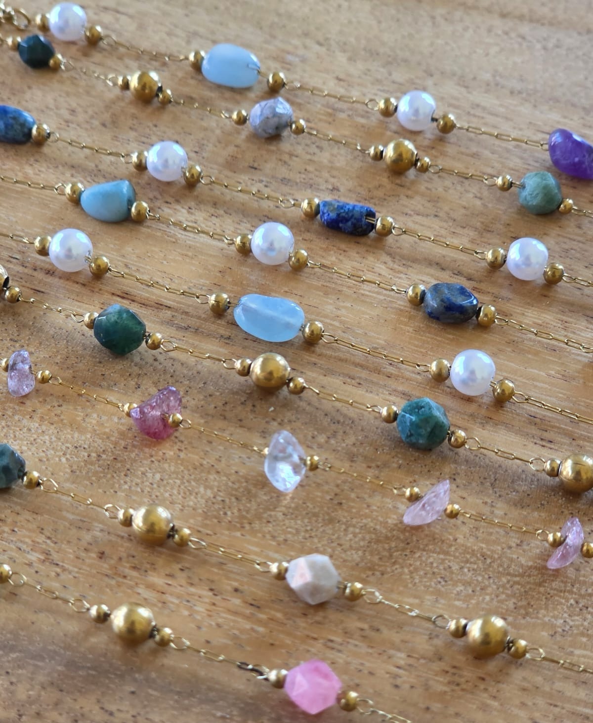 Close-up of gemstone bracelets: amazonite, lapis, rose quartz and brass beads on fine chain